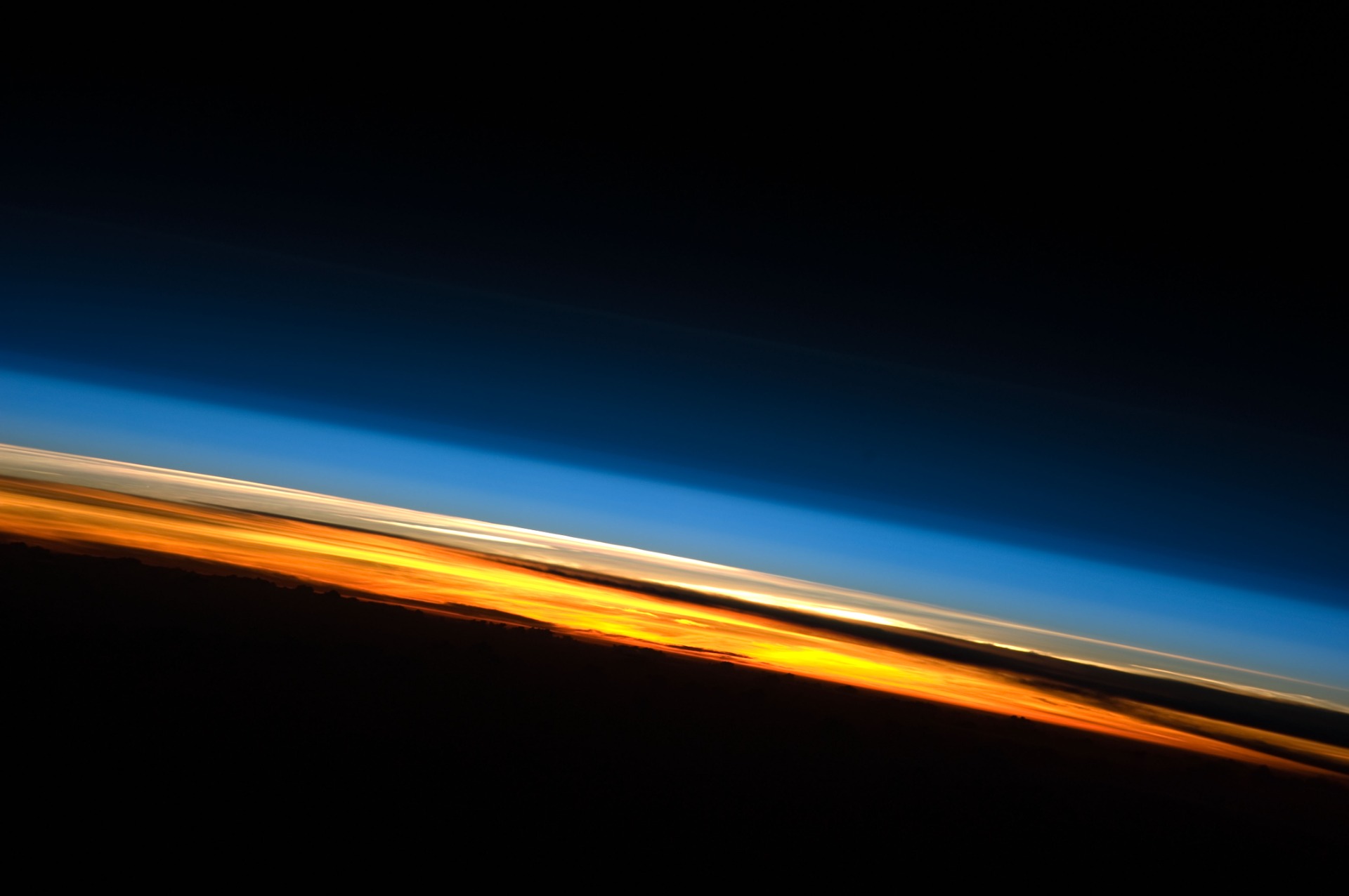 Soloppgang sett fra den internasjonale romstasjonen (ISS) Jordens atmosfære sett fra siden. Fargene definerer omtrentlig lagene i atmosfæren.